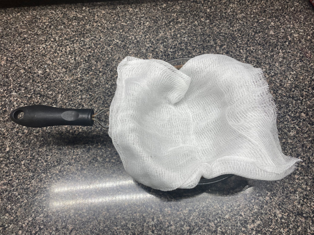 Ir fryer cannoli prep: Cheesecloth set inside a fine mesh strainer, set on top of a medium glass mixing bowl.